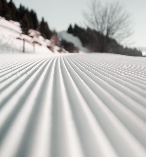 A freshly groomed ski slope under a clear winter sky, ideal for winter sports.